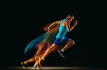 Professional Male Runner Training Isolated On Black Studio Background In Mixed Light. Man In Sportsuit Practicing In Run Or Jogging. Healthy Lifestyle, Sport, Workout, Motion And Action Concept.