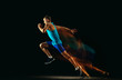 © master1305 - Professional male runner training isolated on black studio background in mixed light. Man in sportsuit practicing in run or jogging. Healthy lifestyle, sport, workout, motion and action concept.