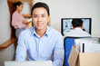 © Seventyfour - Portrait of handsome smiling young Vietnamese businessman working at his table in office of company