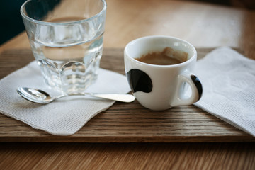 Traditional morning, hot energizing drink. Cup of espresso standing on the brown wooden table.