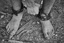Close-up Shot Of Barefoot Legs Tied Up With Old Chain