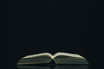 Poster - Open Holy Bible on a black glass table dark background