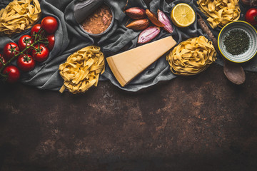 Italian food ingredients for pasta with tuna tomatoes sauce, top view. Copy space. Pasta,parmesan, open tuna can, tomatoes, onion, lemon on dark rustic background.