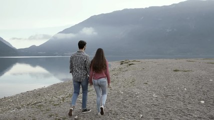 Wall Mural - Young romantic couple holding hands and walking