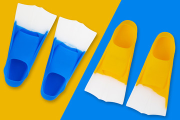 Wall Mural - concept of water sports, two pairs of colored flippers for a pool on a blue and yellow background