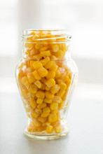 Pile Of Yellow Corn Grains In Glass Jar On Light Background, Close-up
