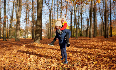 Poster - childhood, season and people concept - happy children having fun at autumn park