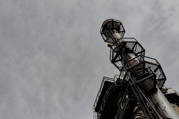 Wall Mural - Extreme upward angled smoke stack against dark gray clouds, copy space, horizontal aspect