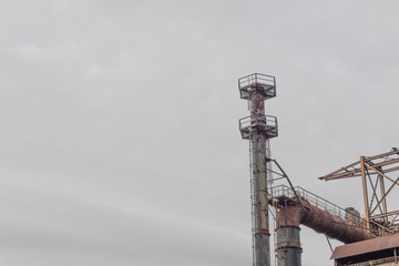 Wall Mural - Industrial site with pipes and smokestacks against a gray sky, ample copy space, horizontal aspect