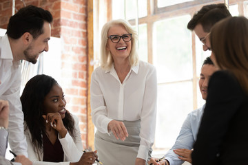 Canvas Print - Happy multicultural young employees with old mentor laughing working together