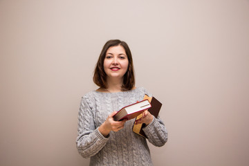 Wall Mural - Portrait of young brunette woman with book in her hand