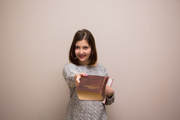 Wall Mural - Portrait of young brunette woman with book in her hand