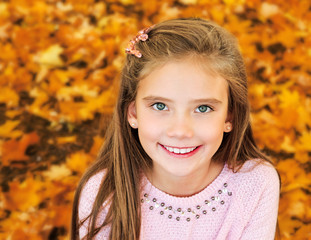 autumn portrait of adorable smiling little girl child with leaves