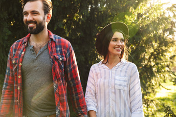 Poster - Image of young couple man and woman smiling and walking in green park