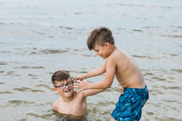 Brothers playing in the ocean water at the beach while on vacation