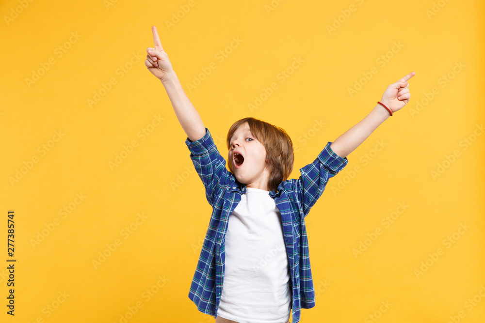 Fun cheerful happy little kid boy in blue shirt white t-shirt posing gesturing hands isolated on yellow wall background children studio portrait. People childhood lifestyle concept. Mock up copy space - obrazy, fototapety, plakaty 