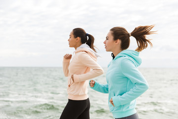 Wall Mural - Two beautiful young fitness women jogging outdoors