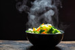 © lesterman - The steam from the vegetables carrot broccoli cauliflower on black bowl , a steaming. Boiled hot Healthy food on table on black background,hot food and healthy meal concept