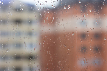 Close up shot of rain drops on glass window against sunset. Raindrops on window against a light background. Raindrops on the window