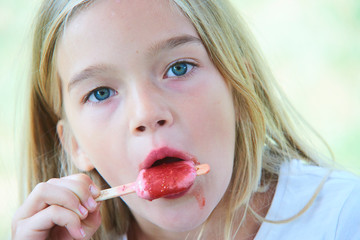 beautiful little girl eats strawberry ice-cream in the summer. selective focus