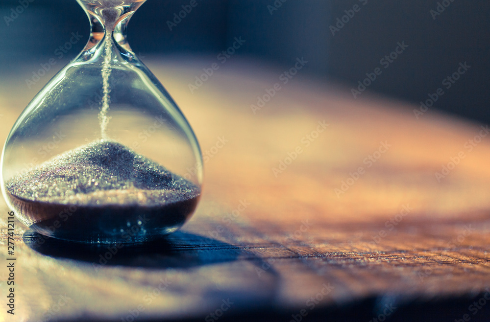 Sand running through the bulbs of an hourglass measuring the passing time in a countdown to a deadline with copy space. - obrazy, fototapety, plakaty 