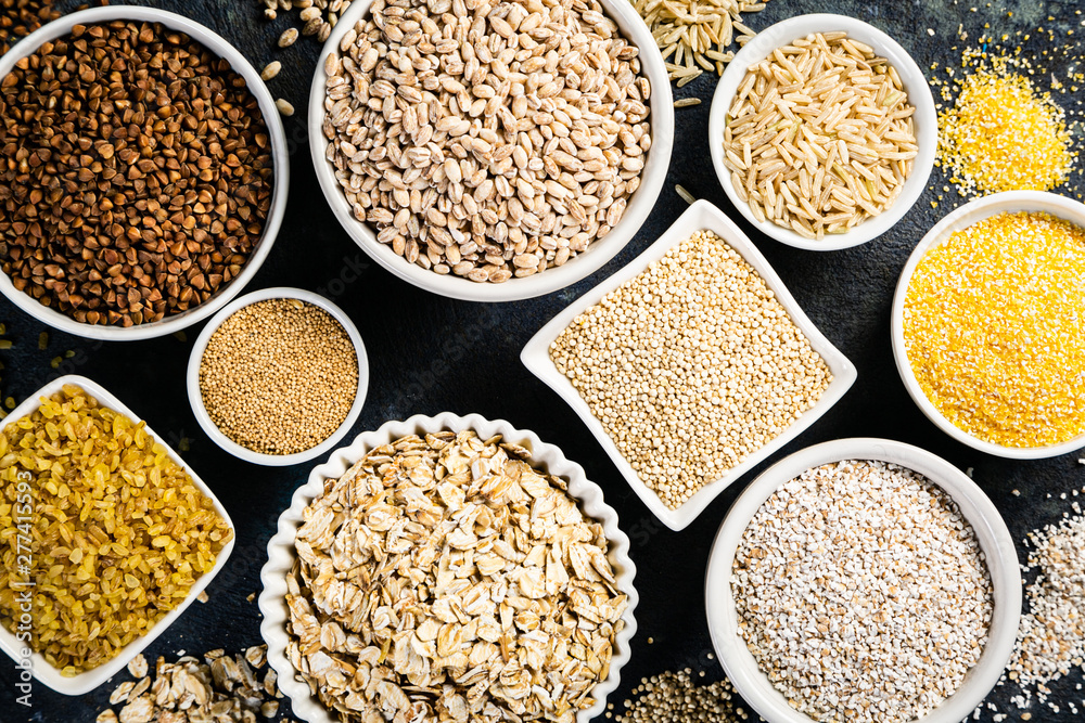 Selection of whole grains in white bowls - rice, oats, buckwheat, bulgur, porridge, barley, quinoa, amaranth on dark background - obrazy, fototapety, plakaty 