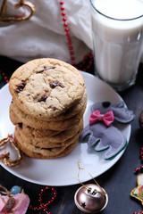 American chocolate cookies, a glass of milk and Christmas decorations. Dark wooden table and pink background. Cookies for the New Year.