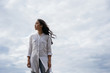 Authentic portrait christian woman breathing fresh air, thinking, makes important life decisions. Asian girl with emotional face standing on background of clouds. Faith in God. Religion concept 
