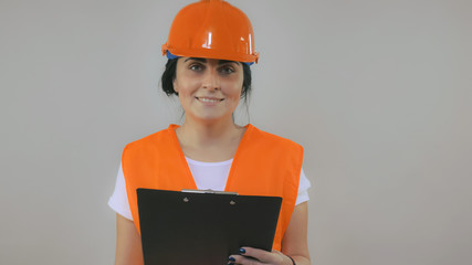 Poster - Adult caucasian woman wearing in hard hat and safety vest orange color working with documents . Portrait builder filling some form.