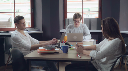 Aufkleber - Meeting young business people in the contemporary office. Professional man and woman discussing project. Smiling employees in startup company sitting at the working place using modern devices