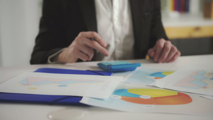 Poster - a man looks at the charts and checks them using a calculator. uhd