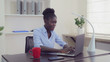 Afro american businesswoman working in office. Young professional woman sitting at the working place typing on computer. Happy manager chatting online or entering data on laptop.