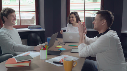 Poster - Business team celebrating victory in the office. Young successful colleagues in startup company glad cry and give five each other at work. Handsome men and happy woman make a deal. Female manager