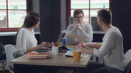 Aufkleber - Young business team celebrating win at the modern creative office. Happy professional people sitting at the working place using computer. Male and female typing on laptop. Smiling employees wearing in
