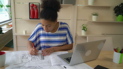 Aufkleber - mixed race worker in architectural agency working with sketch holding pencil and ruler. Young professional woman sitting at the desk.