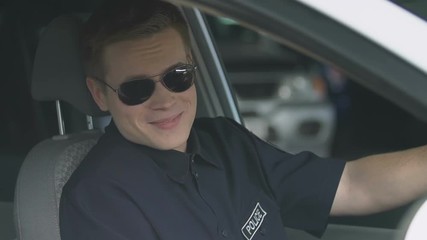 Wall Mural - Responsible policeman in sunglasses sitting in patrol car, smiling to camera