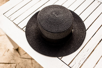 Close-up photo of beautiful woman black summer hat on the white chair.