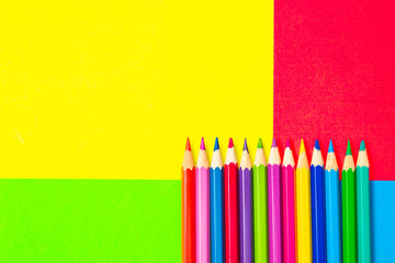 Colorful background with many pencils crayons pastels lined up on multi color backdrop - Top view flat lay