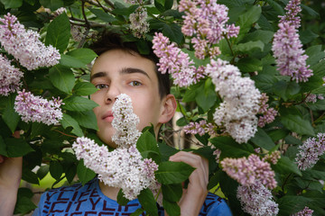 Portrait of Teenage boy in lilac flowers in the park