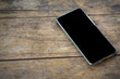 © Nattawit - Smartphone or mobile phone (unrecognized model or brand) is placed on wooden texture surface. Providing display screen as black background for logo space for business concept.