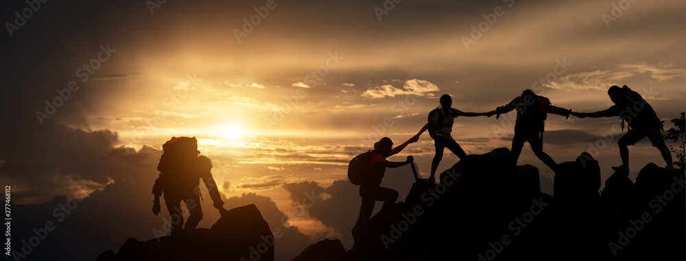 Silhouette of Hikers climbing up mountain cliff. Climbing group helping each other while climbing up in sunset. Concept of help and teamwork, Limits of life and Hiking success full. - obrazy, fototapety, plakaty 