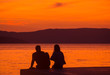 © Inga - a girl and a guy on the pier watching at sunset at the sea