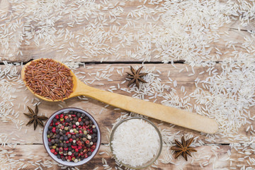 Wall Mural - Brown rice in wooden spoon with peppercorn and star anise on the rustic wooden background