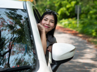 Happy asian women smile to summer holiday travel trip in the car on the road with sunlight, daylight and tree natural background. tourist vacation concept