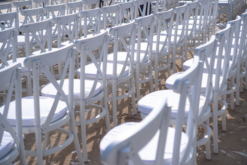 Wall Mural - Rows of white chairs in rows on the beach sand. Conference or outdoor wedding. Watching a movie or a street theater.