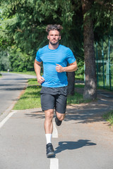 Handsome man running in park with trees in background vertical