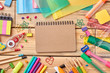 © DenisProduction.com - Notebook and school accessories on wooden background. School supplies on wooden table, top view.