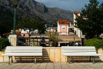 two white benches in charming small resort town at the foot of mountains