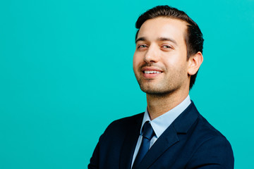 portrait of a confident, smiling man in suit and tie, isolated on blue studio background