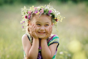  little girl in a wreath of wild flowers in summer